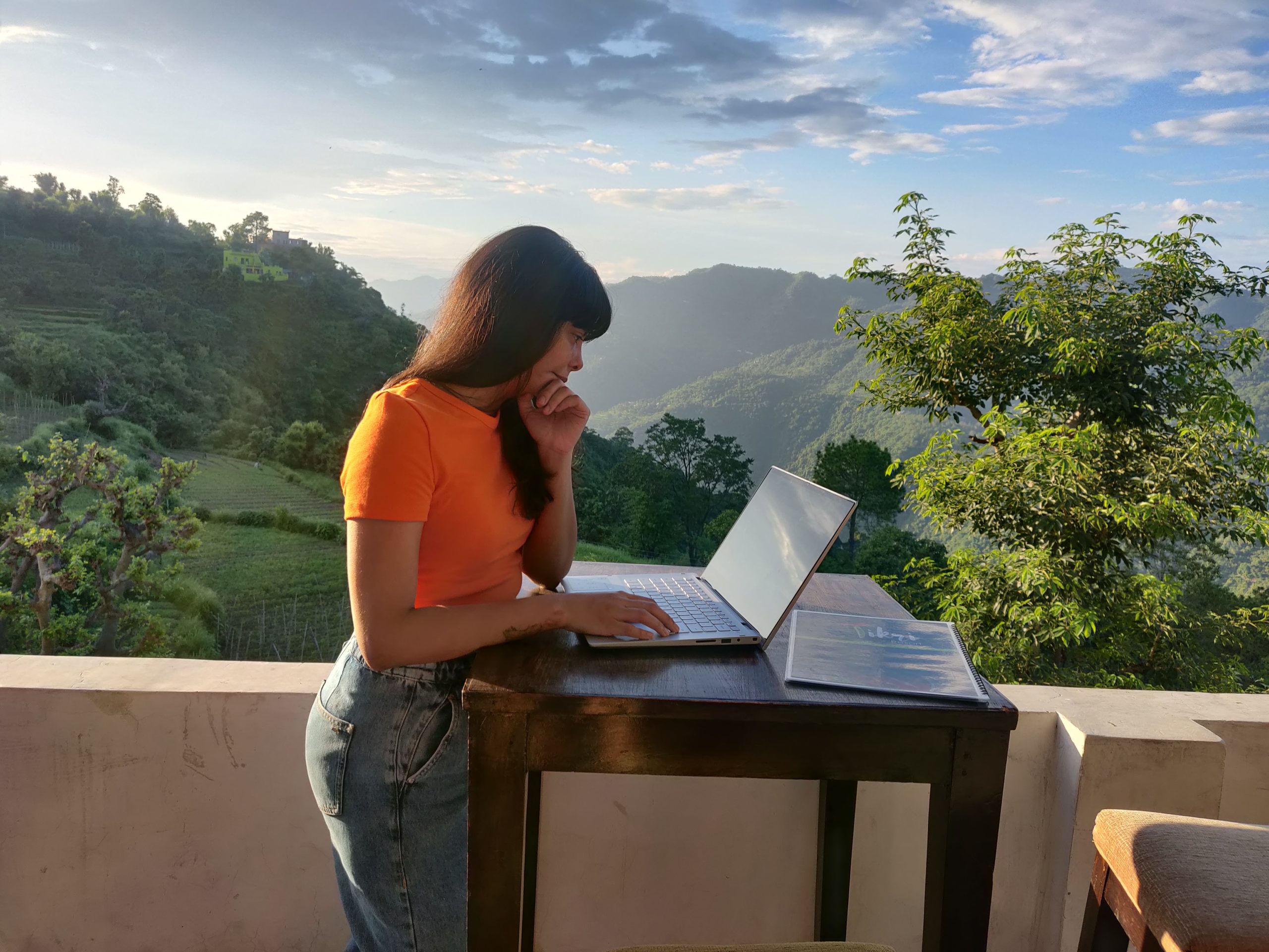 Woman working at standing desk with greenery and mountains in background